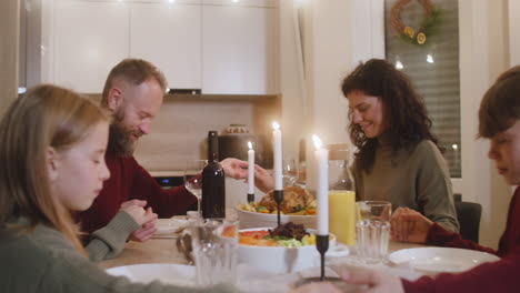Couple-And-Their-Children-Pray-And-Bless-The-Table-Before-Christmas-Family-Dinner-3