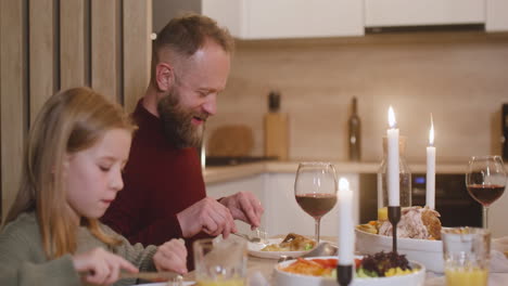 Die-Kamera-Fokussiert-Einen-Vater-Und-Eine-Tochter,-Die-An-Weihnachten-Zu-Abend-Essen,-Am-Tisch-Sitzen-Und-Mit-Anderen-Familienmitgliedern-Sprechen