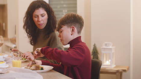 Camera-Focuses-A-Mother-And-Son-Having-Dinner-At-Christmas-Sitting-At-The-Table