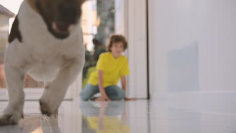 Blond-Boy-With-Curly-Hair-Kneeling-On-The-Floor-While-Playing-With-His-Dog