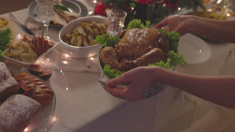 Unrecognizable-Woman-Putting-Roast-Chicken-On-Christmas-Dinner-Table-1
