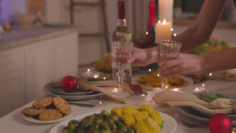 Unrecognizable-Woman-Putting-Two-Champagne-Glasses-On-Christmas-Dinner-Table