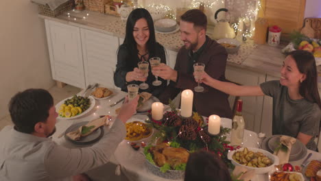 Gruppe-Glücklicher-Freunde,-Die-Am-Tisch-Sitzen-Und-Anstoßen,-Bevor-Sie-Zu-Hause-Das-Weihnachtsessen-Essen-1