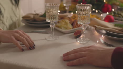 Nahaufnahme-Eines-Nicht-Erkennbaren-Paares,-Das-Beim-Weihnachtsessen-Am-Tisch-Händchen-Hält