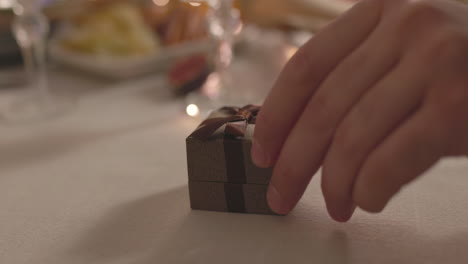 Close-Up-Of-Unrecognizable-Man-Giving-A-Ring-Box-To-Woman-While-Sitting-At-Romantic-Dinner-Table