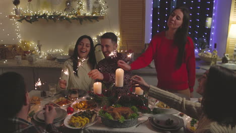 Gruppe-Glücklicher-Freunde,-Die-Sich-Beim-Weihnachtsessen-Zu-Hause-Mit-Wunderkerzen-Amüsieren