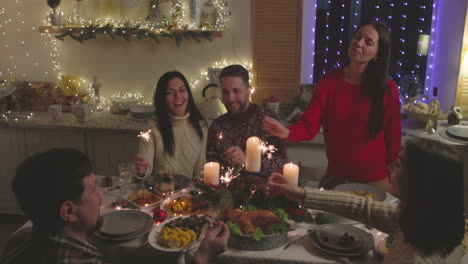 Group-Of-Happy-Friends-Having-Fun-With-Sparklers-During-Christmas-Dinner-At-Home-1