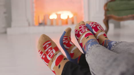 Couple-Feet-In-Cozy-Christmas-Socks-Near-Fireplace-1