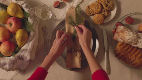 Unrecognizable-Woman-Decorating-A-Napking-With-A-Fir-Twig-For-Christmas-Dinner