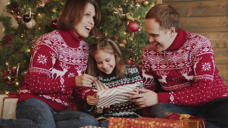 Glückliches-Kleines-Mädchen,-Das-Geschenk-Auspackt,-Während-Es-Mit-Seiner-Mutter-Und-Seinem-Vater-Vor-Dem-Weihnachtsbaum-Zu-Hause-Sitzt-1