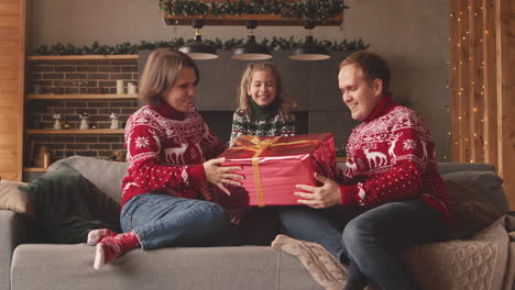 Kleines-Mädchen,-Das-Ihren-Eltern-Am-Weihnachtstag-Zu-Hause-Ein-überraschungsgeschenk-Gibt-2