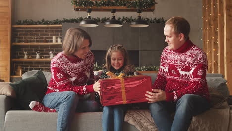 Kleines-Mädchen,-Das-Ihren-Eltern-Am-Weihnachtstag-Zu-Hause-Ein-überraschungsgeschenk-Gibt-3