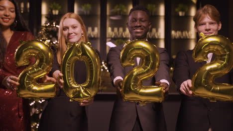 Gruppe-Von-Freunden,-Die-Elegante-Kleidung-Tragen-Und-Luftballons-Mit-Den-Zahlen-2022-Halten,-Während-Sie-Auf-Der-Neujahrsparty-1-Tanzen