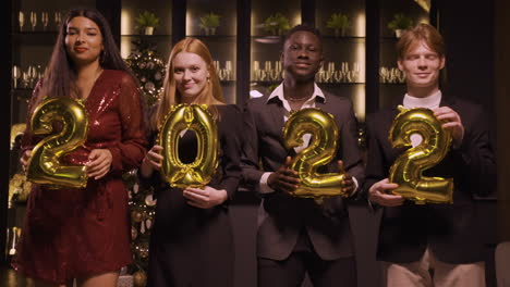 Group-Of-Friends-Wearing-Elegant-Clothes-Holding-Balloons-With-The-Numbers-2022-While-Dancing-In-New-Year's-Party-3