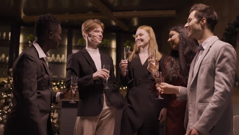 Gruppe-Von-Freunden-In-Eleganter-Kleidung,-Die-Mit-Champagnergläsern-Anstoßen-Und-Einen-Schluck-Auf-Der-Neujahrsparty-Nehmen