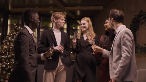 Group-Of-Friends-Wearing-Elegant-Clothes-Toasting-With-Champagne-Glasses-In-New-Year's-Party