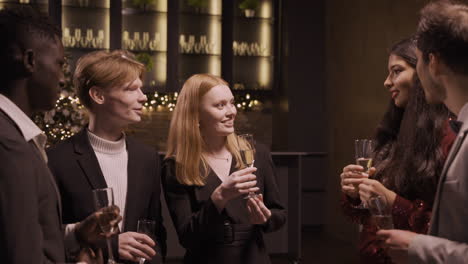 Group-Friends-Wearing-Stylish-Clothes-While-Talking-And-Holding-Champagne-Glasses-At-New-Year's-Party
