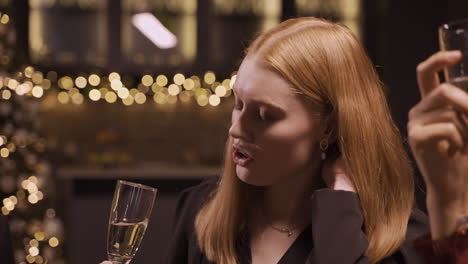 Close-Up-View-Of-A-Red-Haired-Girl-Wearing-Elegant-Clothes-While-Talking-With-Her-Friends-And-Holding-A-Glass-Of-Champagne-At-The-New-Year's-Party-2