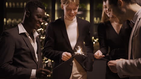Group-Of-Friends-Wearing-Stylish-Clothes-And-Lighting-Sparklers-At-New-Year's-Eve-Party