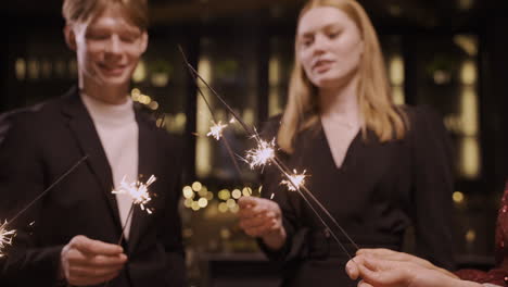Close-Up-View-Of-Group-Of-Friends-Wearing-Stylish-Clothes-Dancing-And-Holding-Sparklers-At-New-Year's-Eve-Party