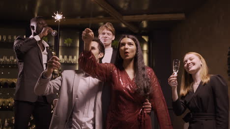 Group-Of-Friends-Wearing-Stylish-Clothes-Celebrating-New-Year-Eve-While-Holding-Sparkles-And-Drinking-Champagne