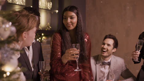 Group-Of-Friends-Dressed-In-Elegant-Clothes-Celebrating-The-New-Year's-Party,-They-Stand-Around-The-Bar-Counter-While-Toasting-And-Drinking-Champagne-1