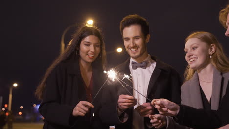 Group-Of-Friends-Wearing-Elegant-Clothes-Lighting-Sparklers-In-The-Street-After-The-New-Year's-Party