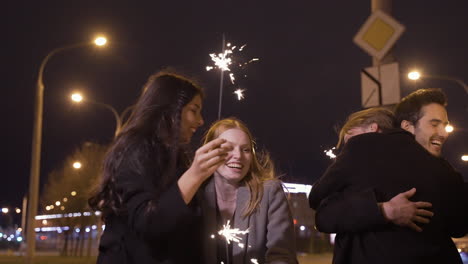 Group-Of-Friends-Wearing-Elegant-Clothes-Holding-Sparklers-And-Hugging-In-The-Street-After-The-New-Year's-Party