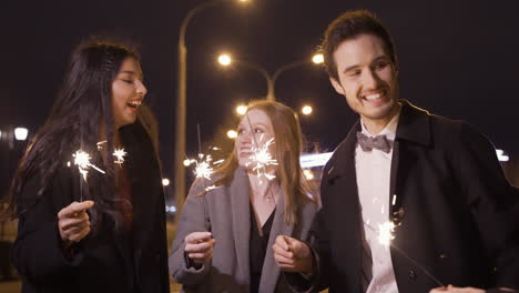 Group-Of-Friends-Wearing-Elegant-Clothes-Holding-Sparklers-In-The-Street-After-The-New-Year's-Party