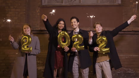 Gruppe-Von-Freunden-In-Eleganter-Kleidung-Mit-Wunderkerzen-Und-2022-Nummern-Goldenen-Ballons-Auf-Der-Straße-Nach-Der-Neujahrsparty