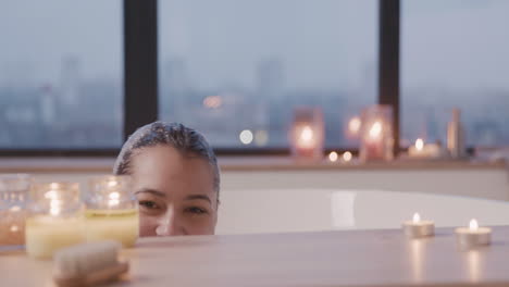 Woman-Hiding-Behind-A-Wooden-Table-Smiling-At-Camera-While-Taking-A-Bath
