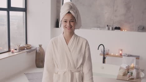 Front-View-Of-A-Woman-Posing-And-Smiling-At-The-Camera-With-A-Towel-On-Her-Head-And-A-Bathrobe