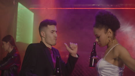 Happy-Multiethnic-Couple-Drinking-Beer-And-Dancing-At-Disco-2