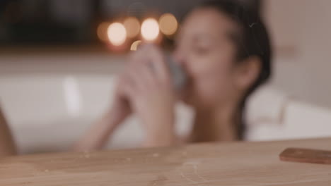 Close-Up-View-Of-A-Table-With-Candles-And-Incense,-In-The-Background-A-Blurred-Woman-Taking-A-Bath-And-Drinking-1