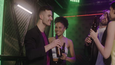 Group-Of-Four-Young-Friends-Dancing-And-Drinking-Beer-At-Disco