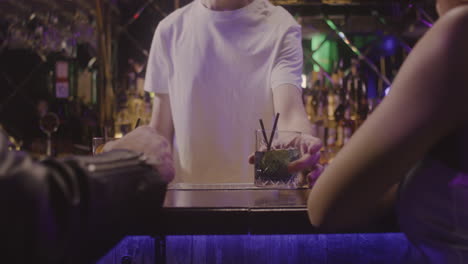 Close-Up-Of-Waiter-Serving-Drinks-To-Unrecognizable-Couple-Sitting-At-Bar-Counter