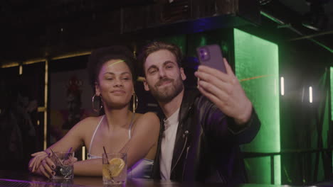 Multiethnic-Couple-Taking-A-Selfie-Photo-While-Sitting-At-Bar-Counter