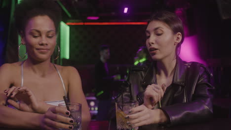 Dos-Chicas-Multiétnicas-Bebiendo-Y-Hablando-Entre-Ellas-En-El-Mostrador-Del-Bar