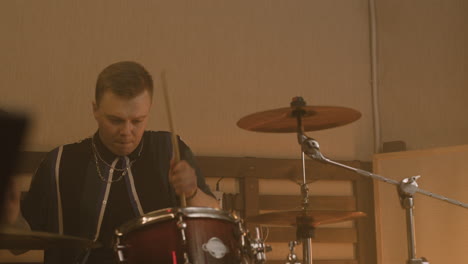 Male-Musician-Playing-Drums-During-A-Band-Rehearsal-In-Recording-Studio-2