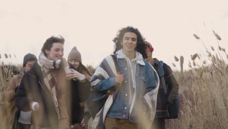 Front-View-Of-A-Group-Of-Teenage-Boys-And-Girls-Wearing-Winter-Clothes-Walking-In-A-Wheat-Field-On-A-Cloudy-Day-1