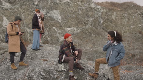 Group-Of-Teenage-Friends-Dressed-In-Winter-Clothes-Talking-And-Using-Smartphone-On-The-Mountain