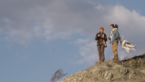 Two-Teenage-Boys-In-Winter-Clothes-Talking-On-Top-Of-A-Mountain-On-A-Windy-Day