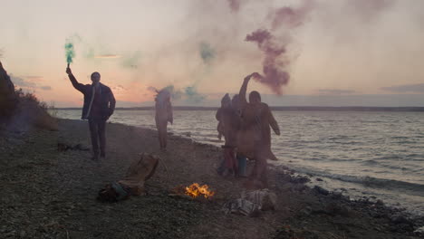 Group-Of-Teenage-Friends-Running-Around-A-Bonfire-Holding-Colored-Sparklers-On-The-Seashore