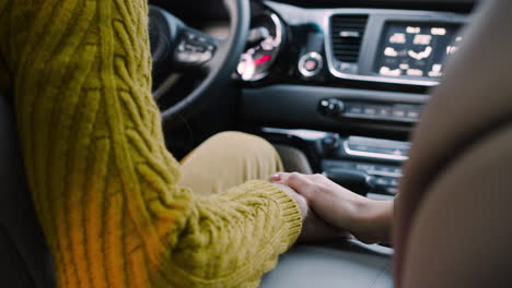 Camera-Focuses-On-The-Hand-Of-A-Woman-Grabbing-Her-Husband's-Hand-On-The-Armrest-Of-A-Car