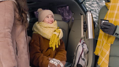 Teenager-Mädchen-In-Winterkleidung-Sitzt-Im-Kofferraum-Eines-Autos,-Während-Sie-Mit-Ihren-Eltern-Spricht