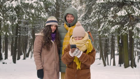 Mädchen-Fotografiert-Mit-Smartphone-In-Winterkleidung-Im-Verschneiten-Wald-1
