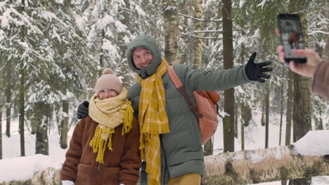Rear-View-Of-A-Woman-Taking-A-Photo-Of-Her-Husband-And-Daughter-In-The-Snowy-Forest