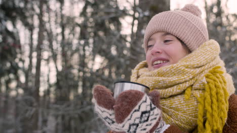 Close-Up-View-Of-A-Girl-In-Winter-Clothes-Drinking-Tea-In-The-Snowy-Forest