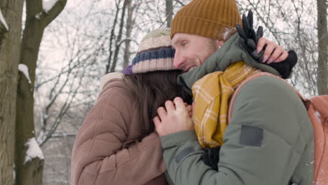 Husband-And-Wife-In-Winter-Clothes-Warm-Their-Hands-With-Their-Mouths-In-A-Snowy-Forest