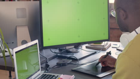 Graphic-Designer-Using-Digital-Drawing-Tablet-And-Looking-At-Monitor-With-Green-Screen-In-An-Animation-Studio